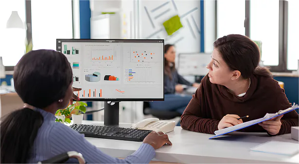 Two colleagues reviewing student analytics dashboards on a monitor